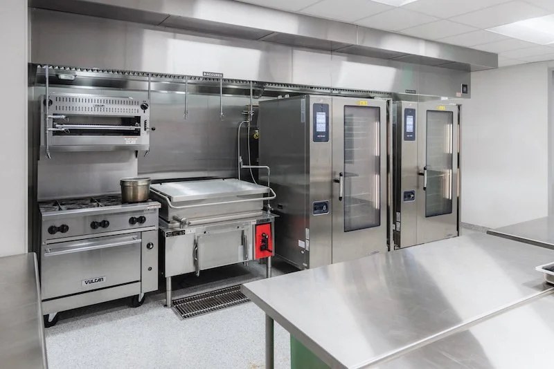 A commercial kitchen with ranges, ovens, and steamers serviced by 7K Mechanical